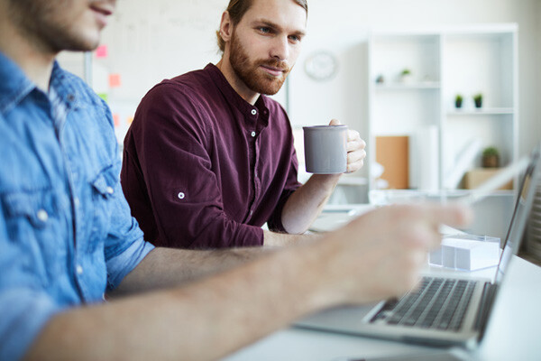 SEO specialist sat with client holding a cup of coffee checking client's website